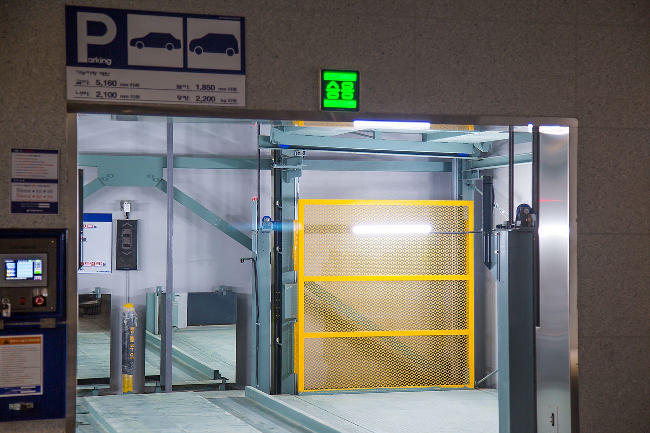 A parking garage entrance with a sign indicating parking rates and a green exit sign.