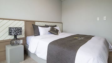 A neatly arranged bedroom with a bed, a bedside table, and a nightstand.