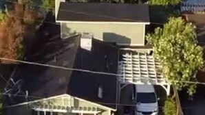 A two-story house with a garage and a driveway, surrounded by trees and a body of water.