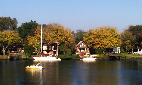 A lakeside view with boats, a house, and trees.