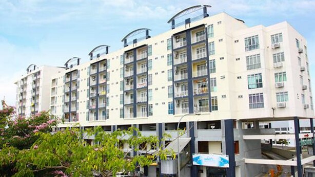 A multi-story residential building with balconies, large windows, and a flat roof design.