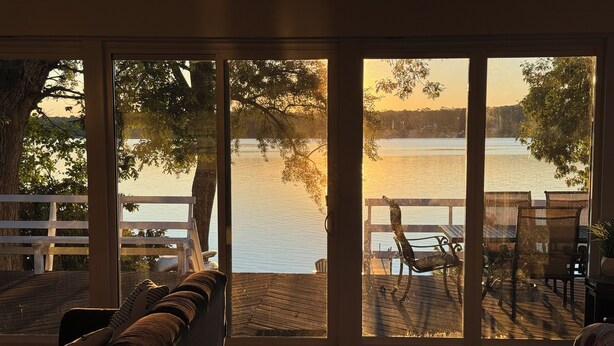 A room with a large sliding glass door leading to a deck overlooking a lake. - Cozy Lakefront Home - 278 FIVE STAR Reviews - Kayaks, Sunsets & Panoramic Views (Newburgh)