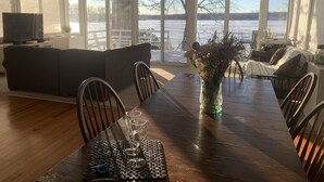A dining area with a wooden table, chairs, and a vase of flowers. - Cozy Lakefront Home - 278 FIVE STAR Reviews - Kayaks, Sunsets & Panoramic Views (Newburgh)