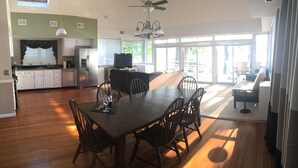 A spacious kitchen with white cabinets, a dining area with a wooden table and chairs, and a large sliding glass door leading to a patio. - Cozy Lakefront Home - 278 FIVE STAR Reviews - Kayaks, Sunsets & Panoramic Views (Newburgh)