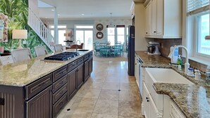 A spacious kitchen with a large island, granite countertops, and modern cabinetry. - Oceans 111 | Oceanfront with Elevator + Direct Beach Access! (Topsail Beach)