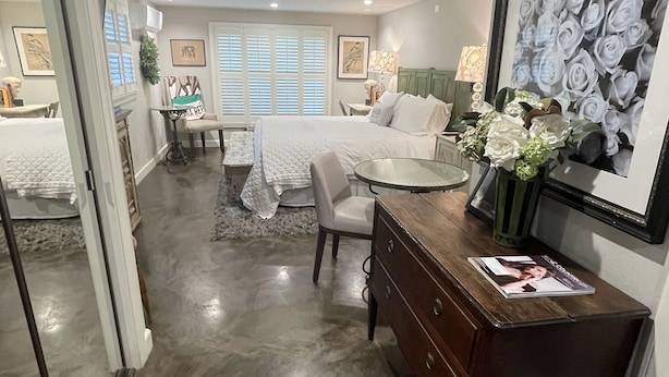 A modern bedroom with a large bed, a desk, and a dining area.