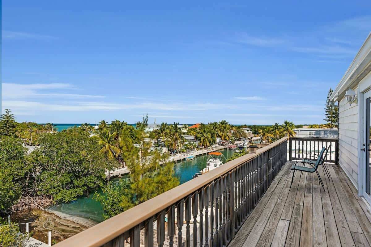A wooden deck with a view of a marina and palm trees.
