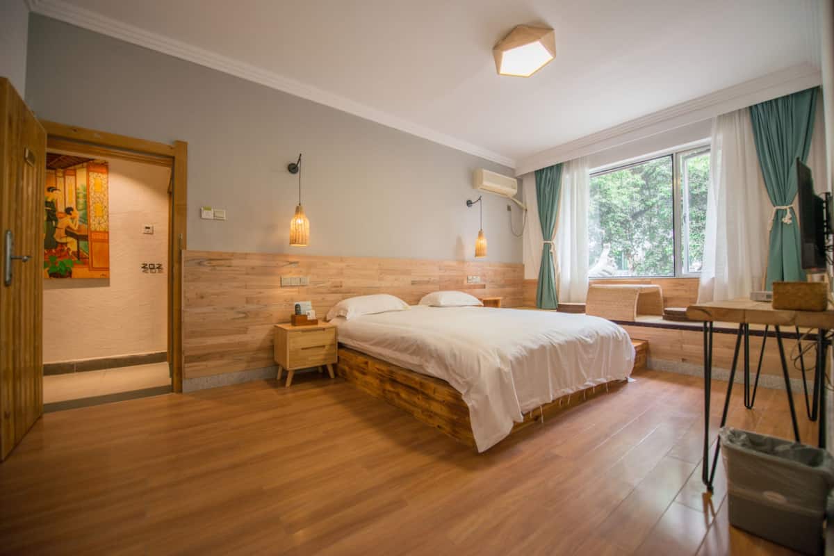A bedroom with a wooden bed, bedside tables, a desk, and a window with curtains.