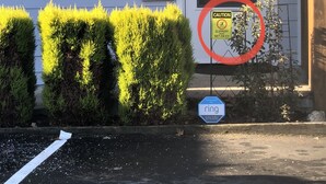 A residential area with a caution sign for slippery conditions when wet or icy, a 'ring' surveillance sign, and a mailbox with the number 2.