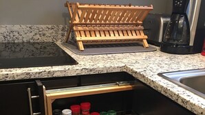 A kitchen with a built-in spice rack, a coffee maker, and a wooden drying rack.