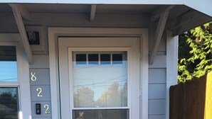 A white front door with a window above it, a mailbox, and a wooden fence to the right.