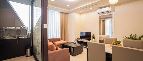 Une chambre d’hôtel moderne équipée d’une kitchenette, d’un canapé, d’un coin repas et d’une télévision.