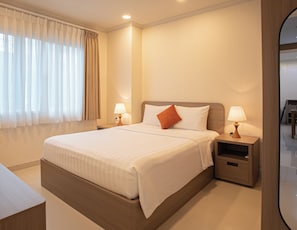 A hotel room with a large bed, two bedside tables with lamps, a nightstand, and a mirror. - Mayfair Suites (Ho Chi Minh City)