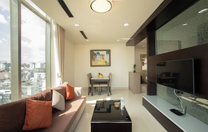 A modern living room with a sofa, dining table, and a large TV. - Mayfair Suites (Ho Chi Minh City)