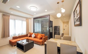 Uma sala de estar moderna com um sofá seccional, uma mesa de centro e uma área de jantar com mesa de mármore.
