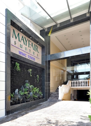 A hotel entrance with a sign for Mayfair Suites, Wing Tower, and a staircase leading to the upper level. - Mayfair Suites (Ho Chi Minh City)