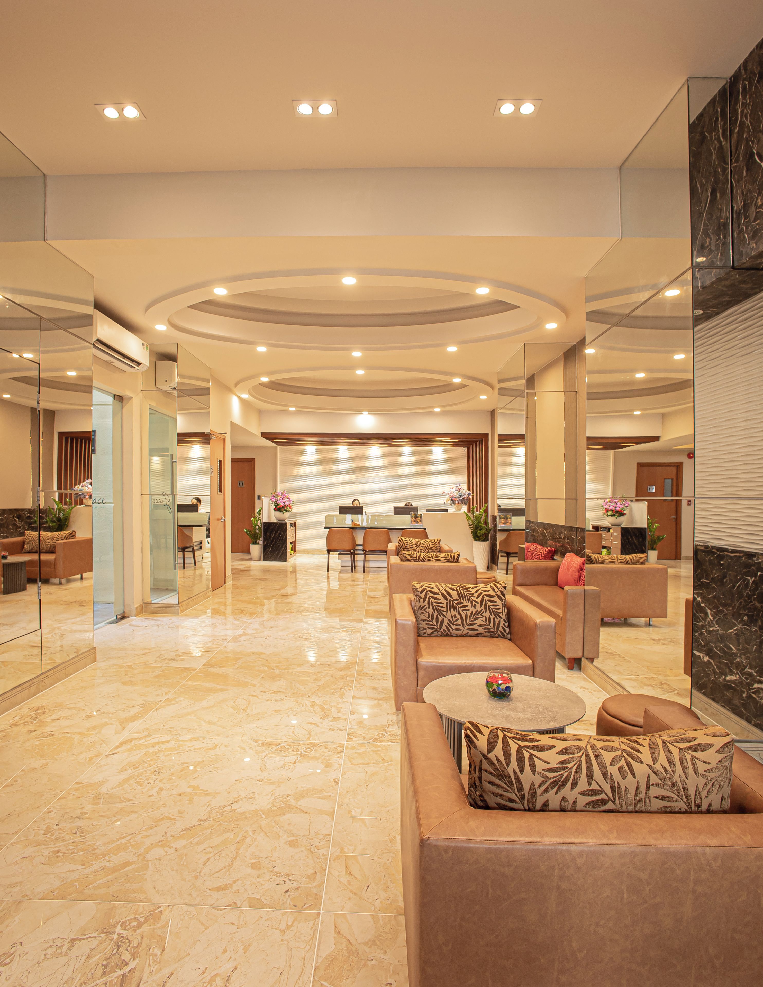 A spacious lobby with a marble floor, multiple seating areas, and a reception desk in the background.