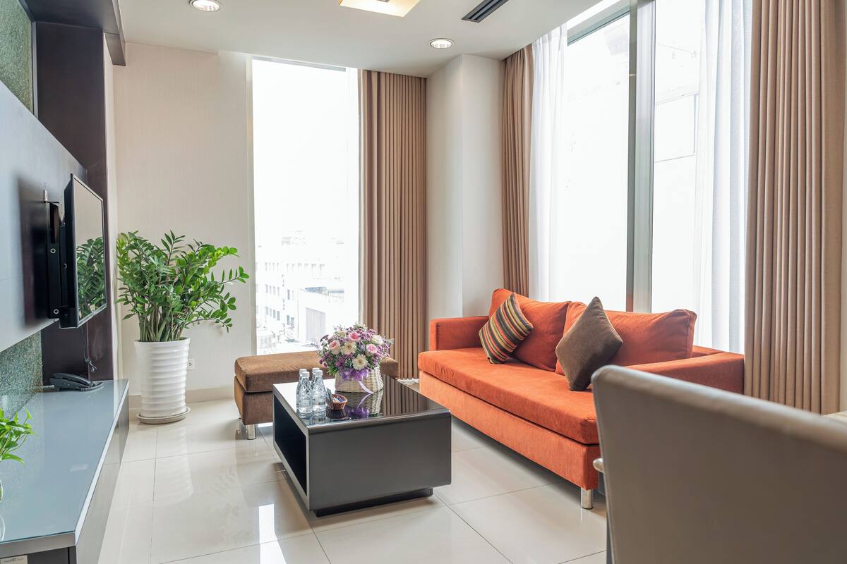 A modern living room with a sofa, a coffee table, a TV, and a potted plant.