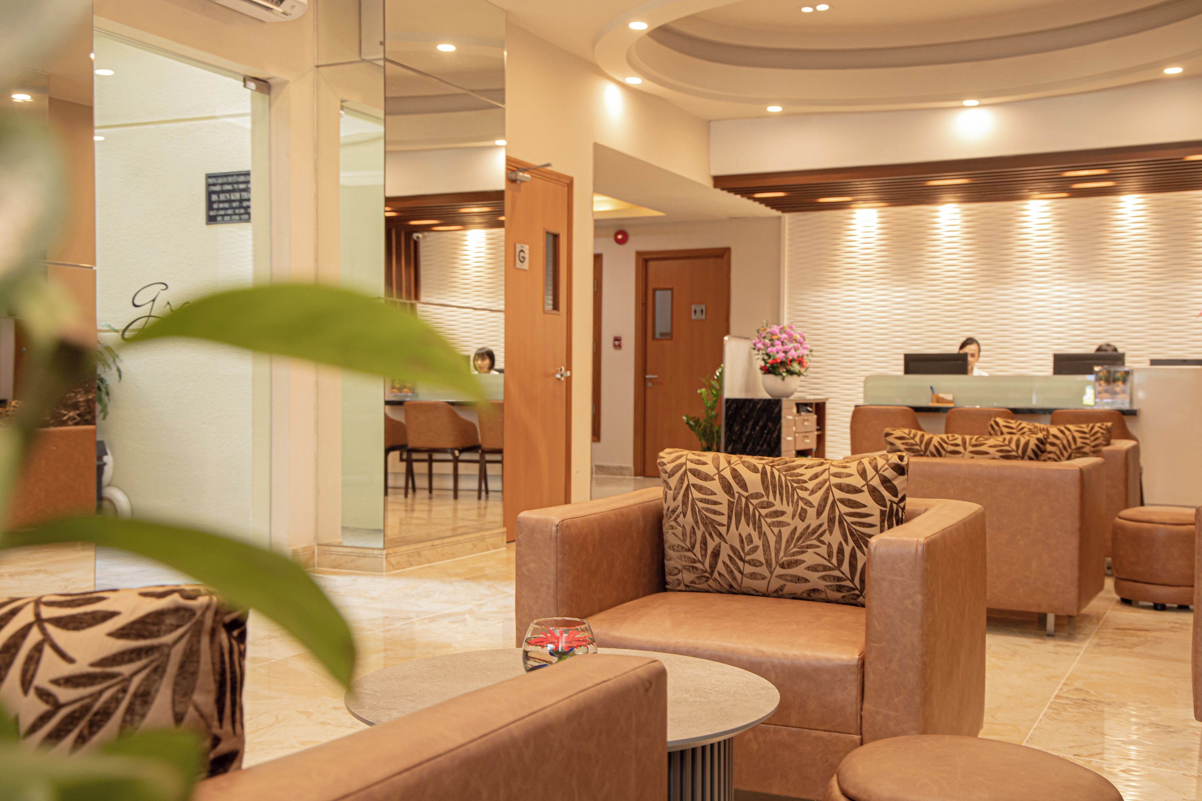 A modern lobby with leather sofas, a reception desk, and a glass partition.
