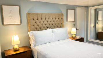 A neatly made bed with white linens, a tufted headboard, and two bedside lamps on wooden nightstands.