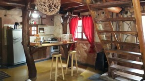 A rustic kitchen with wooden beams, a hanging light fixture, a refrigerator, a stove, and a wooden ladder. - Lajas del Puerto (San Ignacio)