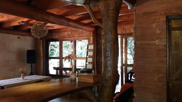 A rustic wooden interior with a wooden table, a vase with flowers, and a stone wall. - Lajas del Puerto (San Ignacio)