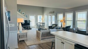 A modern kitchen with white cabinetry, a central island, and a dining area with chairs and a table. - Long Grass 5 Bedroom Home by RedAwning (Supply)