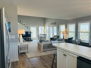 A modern kitchen with white cabinetry, a central island, and a dining area with chairs and a table.