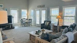 A living room with a TV, dining table, chairs, a sofa, and a sign that reads 'Pops Place'. - Long Grass 5 Bedroom Home by RedAwning (Supply)