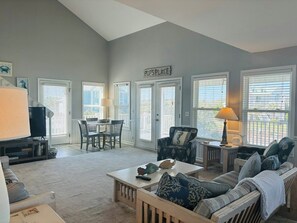 A living room with a TV, dining table, chairs, a sofa, and a sign that reads 'Pops Place'.