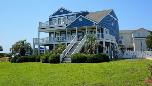 A two-story house with a balcony, a staircase, and a white picket fence. - Long Grass 5 Bedroom Home by RedAwning (Supply)