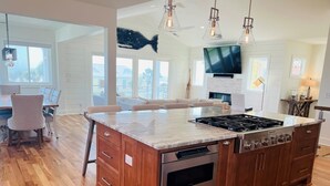 A modern kitchen with a central island, wooden cabinets, and a built-in oven. - The Rainbow Connection 4 Bedroom Home by RedAwning (Supply)