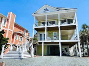 A multi-story building with a balcony on the second floor, a staircase leading to the entrance, and a number '165' on the facade.