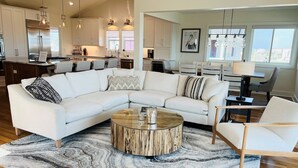 A modern living room with a sectional sofa, a round coffee table, and a marble-patterned rug. - The Rainbow Connection 4 Bedroom Home by RedAwning (Supply)