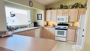 A kitchen with a central island, a microwave, an oven, and a sink.