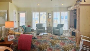 A living room with a patterned sofa, two armchairs, a ceiling fan, and a television.
