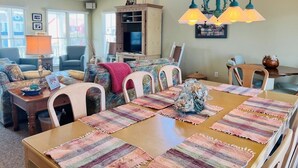 A dining area with a wooden table, colorful placemats, and a chandelier.