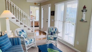 A living room with a staircase, two wicker chairs, a blue sofa, and a coffee table.
