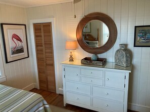 Een kamer met een bed, een dressoir met lades, een spiegel, een lamp en twee wandplaten.