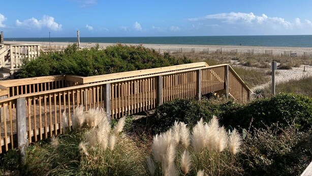 A wooden deck with a view of the beach and ocean.