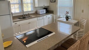 A kitchen with white cabinets, a built-in microwave, a stove, and a dining area with a table and chairs.