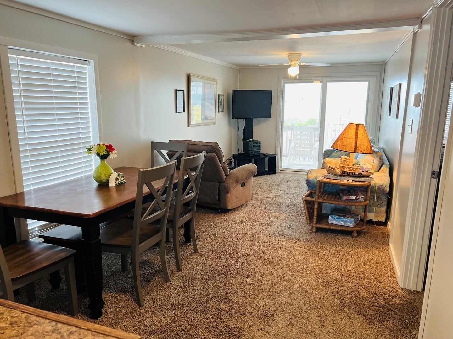 A living room with a TV, sofa, and a dining area with chairs and a table.