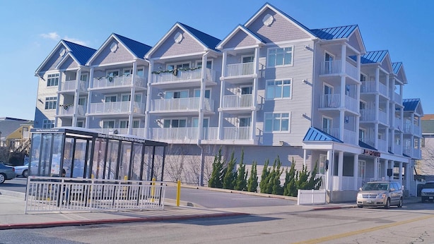A multi-story hotel with balconies, a covered entrance, and a parking area. - Bel Mare 100 4 Bedroom Condo by RedAwning (Ocean City)