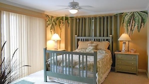 A bedroom with a bed, a nightstand, a ceiling fan, and a window with blinds. - Bel Mare 100 4 Bedroom Condo by RedAwning (Ocean City)