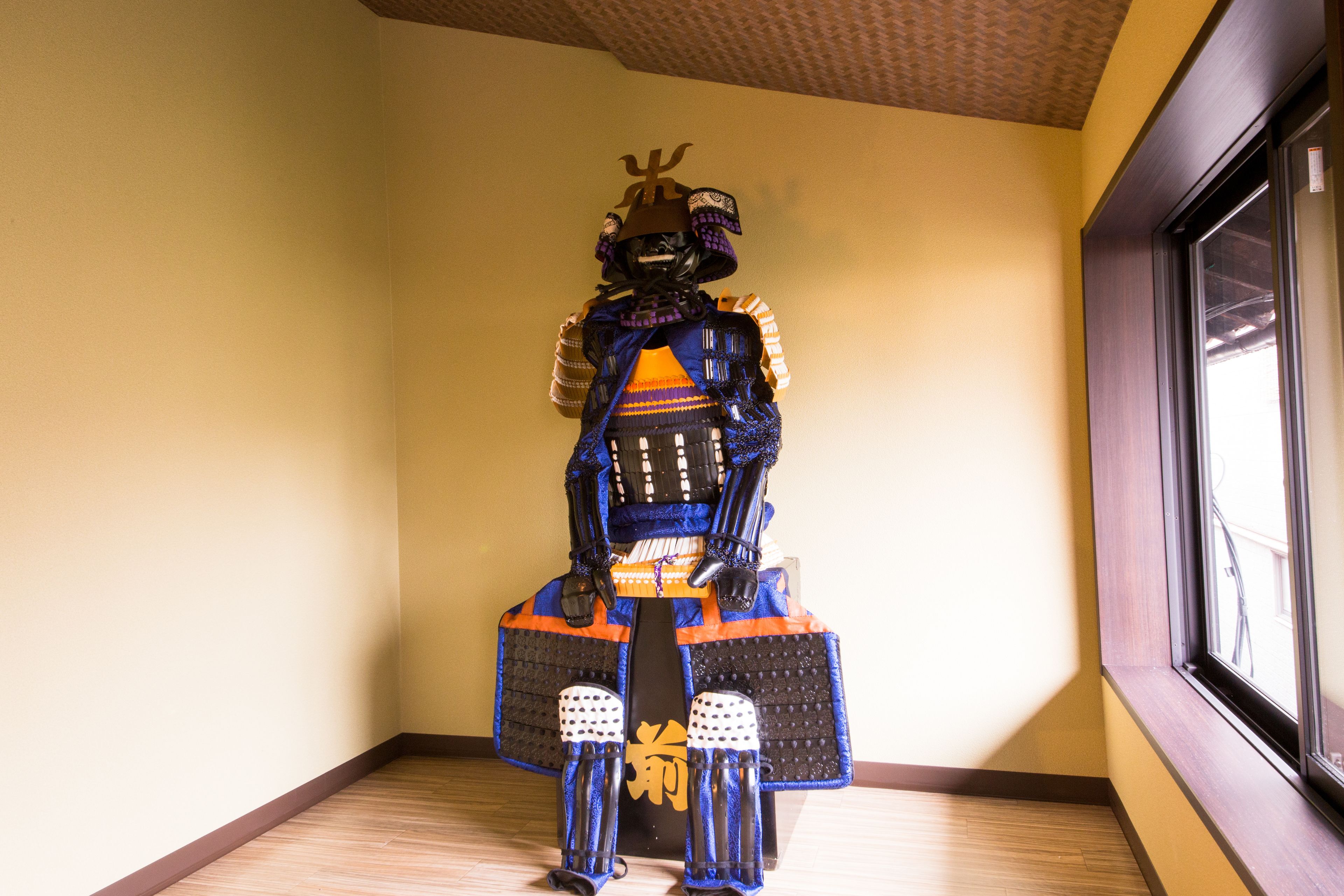 A room with a large window, a wooden floor, and a wall-mounted decorative item.