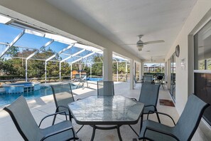 A covered outdoor area with a pool, seating, and a view of the surrounding landscape.