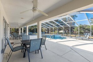 A covered outdoor area with a pool, chairs, and tables. - North Timucuan Trail 1208 3 Bedroom Villa by RedAwning (Inverness)