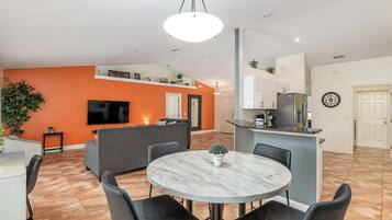 A modern living space with a dining area, kitchen, and entertainment area.