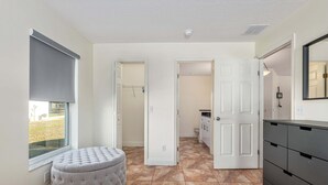 A hallway with a round ottoman, a white door, and a window with a blind. - North Timucuan Trail 1208 3 Bedroom Villa by RedAwning (Inverness)