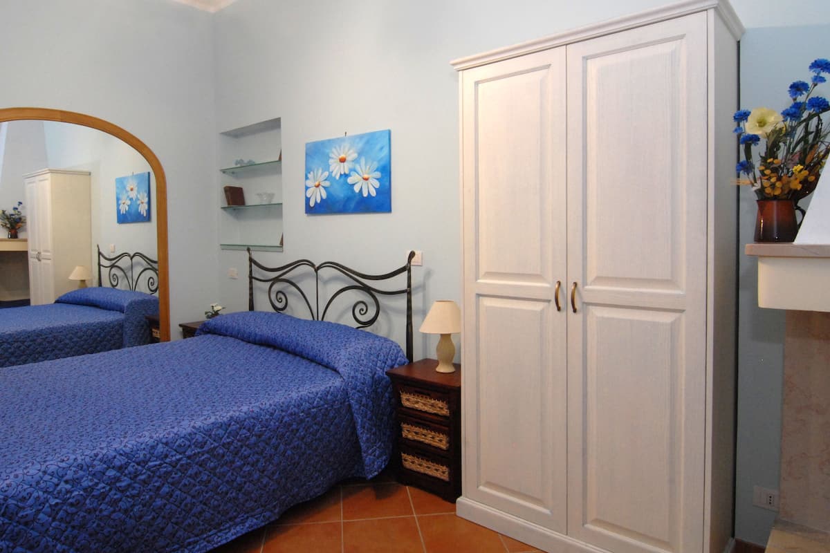 Ein Schlafzimmer mit zwei Betten, einem Kleiderschrank, einem Spiegel und einem Bild an der Wand.
